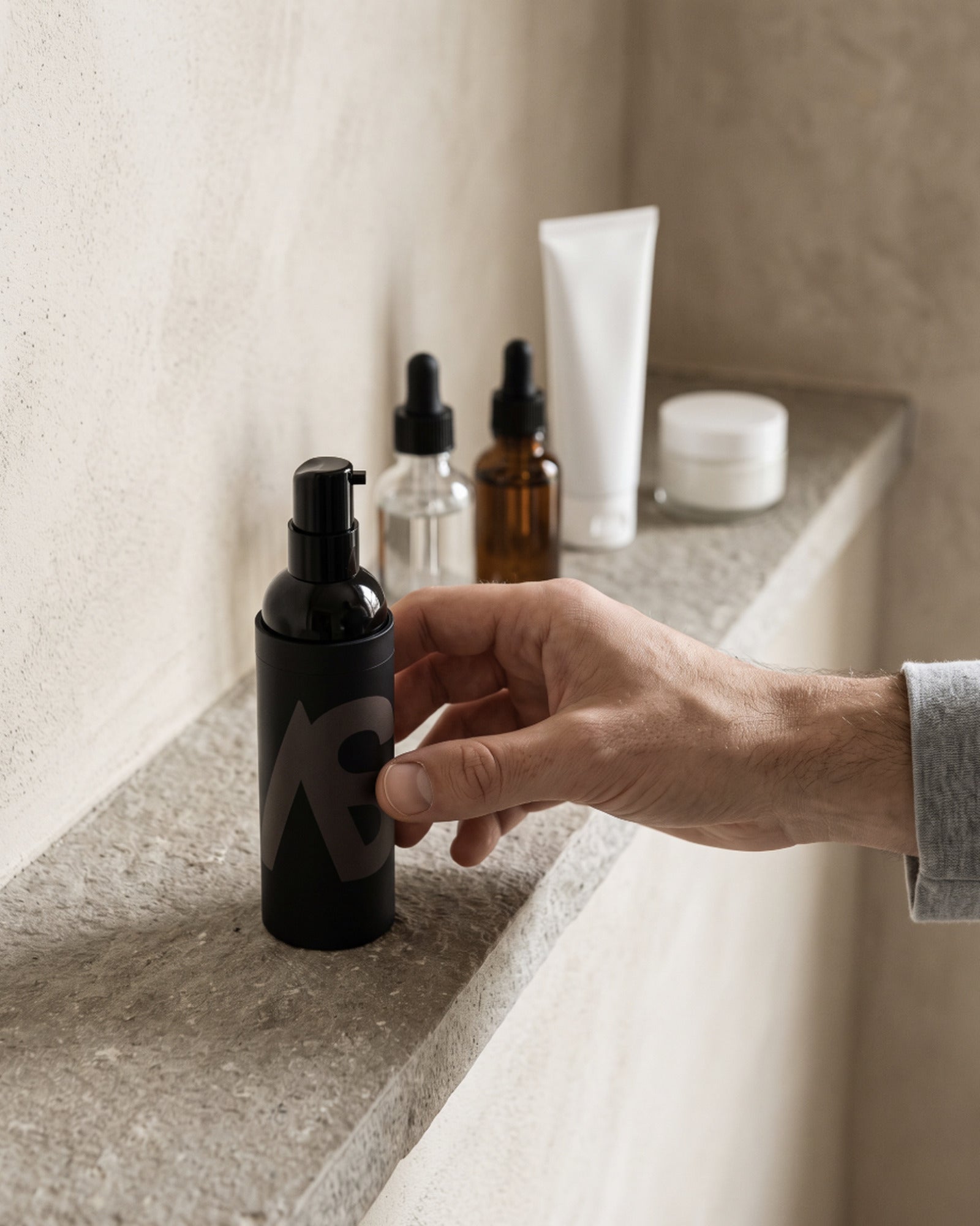 A man's hand reaching for the Stealth Blender bottle on a stone shelf