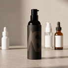 Stealth Blender pump bottle on a stone bathroom counter with other skincare bottles behind it
