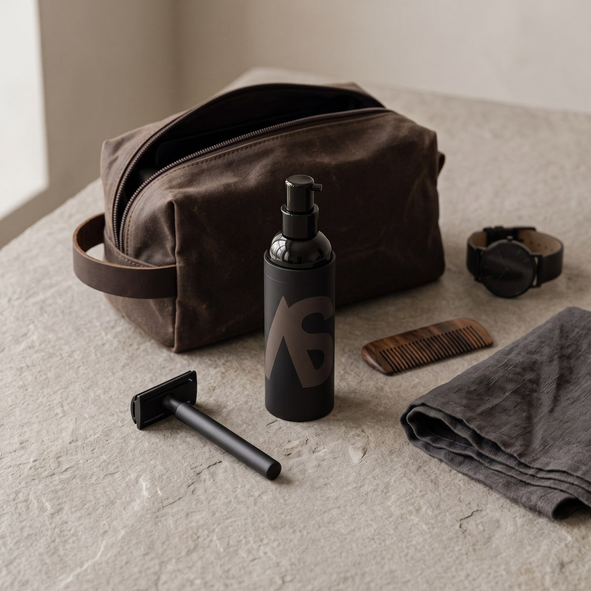 Stealth Blender bottle with a waxed canvas dopp kit, razor, comb and watch on stone